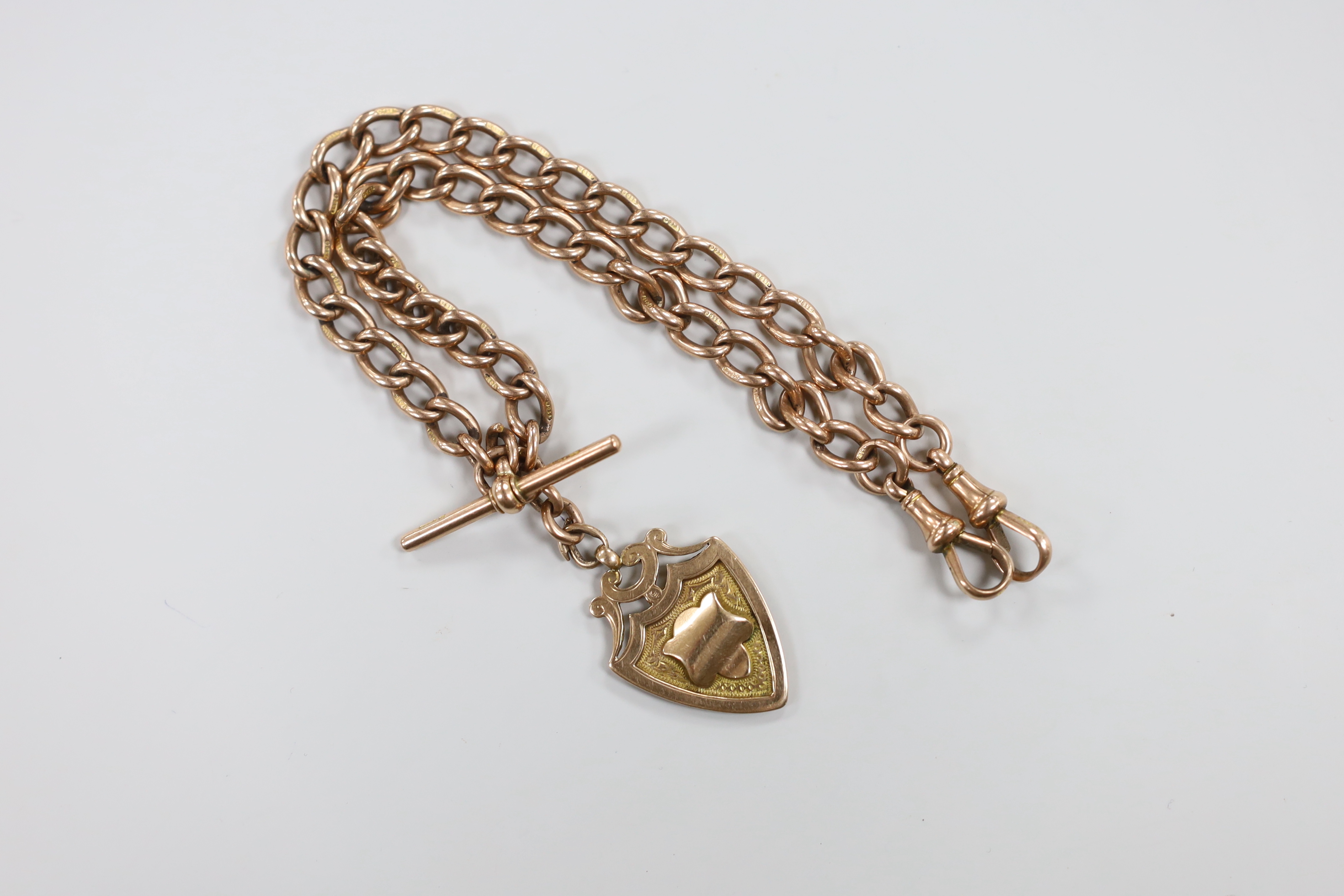 An early 20th century 9ct rose gold albert, 36cm, hung with a 9ct gold shield shaped medallion, 52.3 grams.